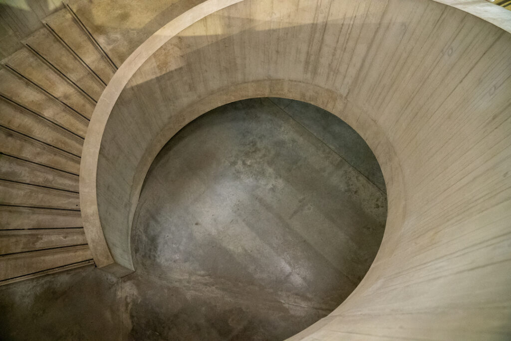 Top-down view of a concrete spiral staircase and circular floor design in a modern architectural space.