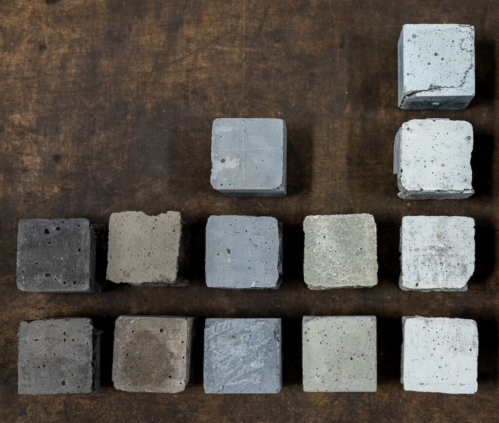 Various concrete cube samples displayed on a wooden surface, showcasing different colours and textures.